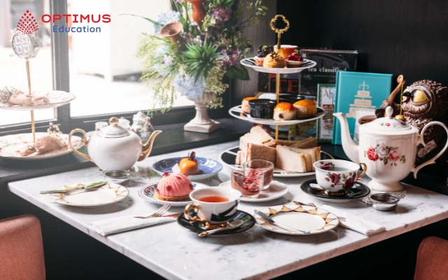 Afternoon Tea truyền thống với khay 3 tầng: Bánh mỳ sandwich nhỏ ở dưới cùng, bánh scone ở giữa và bánh ngọt ở trên cùng.
